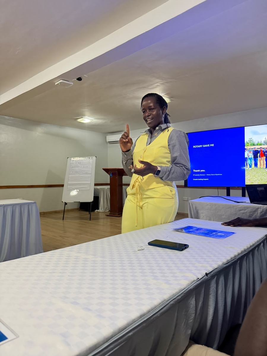 The Membership Director speaking to the club beside a slide that reads “Rotary gave me”.