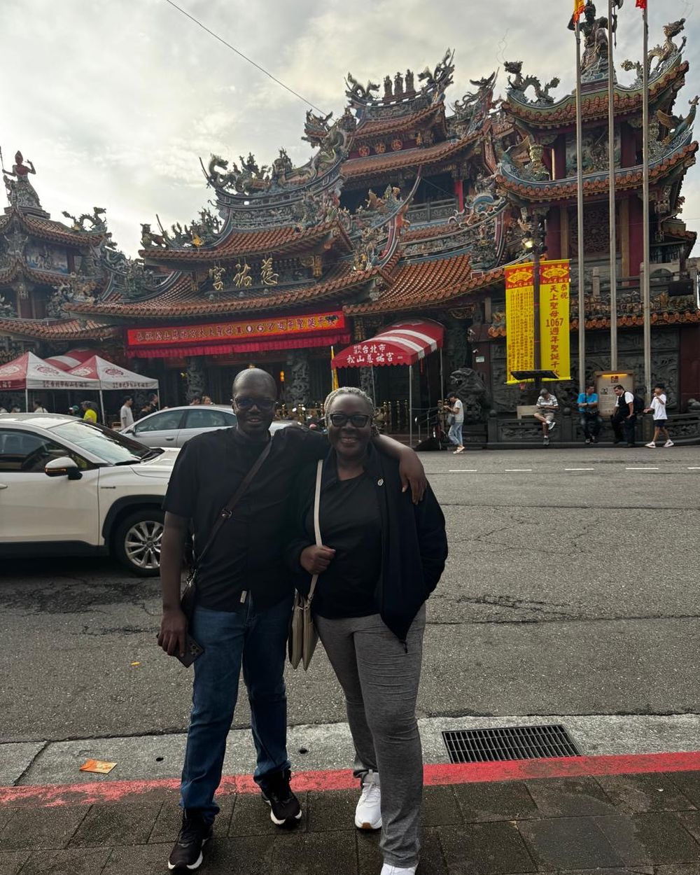 IPP Barrack Odero and Rtn. Victoria Ojoo standing together on a Taipei street, an ornate temple rising behind them