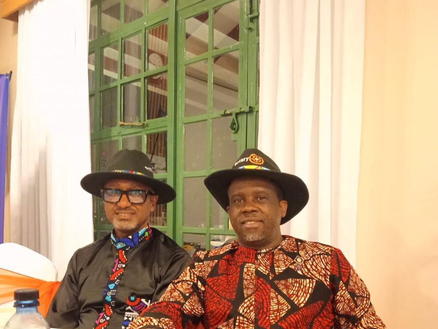 Two Rotarians in Rotary-branded hats seated together at a club event