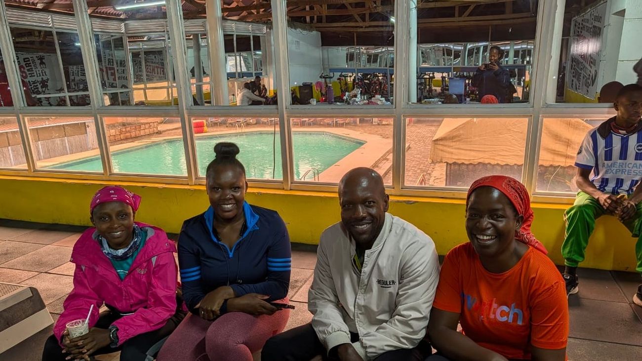 Four members in activewear seated together after the fitness session, poolside at the gym