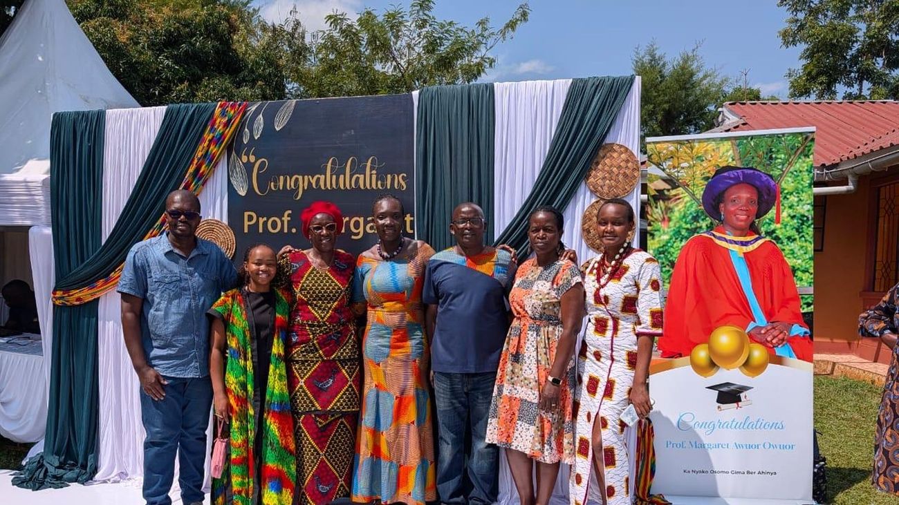 Rtn. Prof. Margaret Awuor Owuor with family and friends beside a congratulations backdrop in Siaya