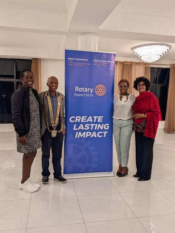 District Governor Esayas Yeyesuswork with members beside the Create Lasting Impact banner