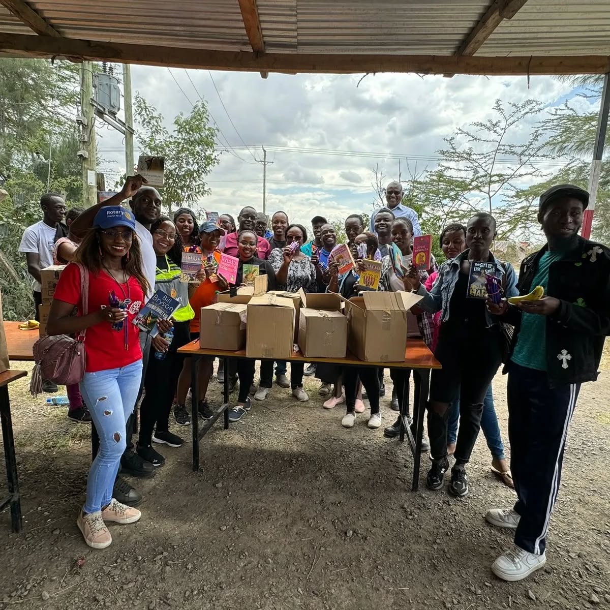 Club members and community members standing behind a table of boxed books, holding up donated titles.