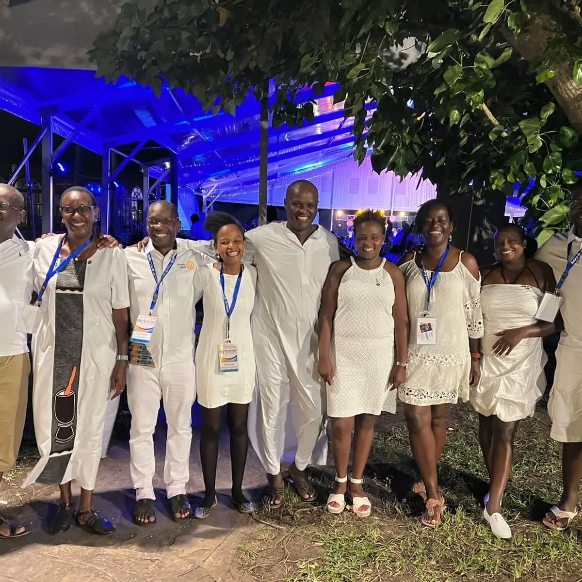 Club members dressed in white standing arm in arm at an evening district event.