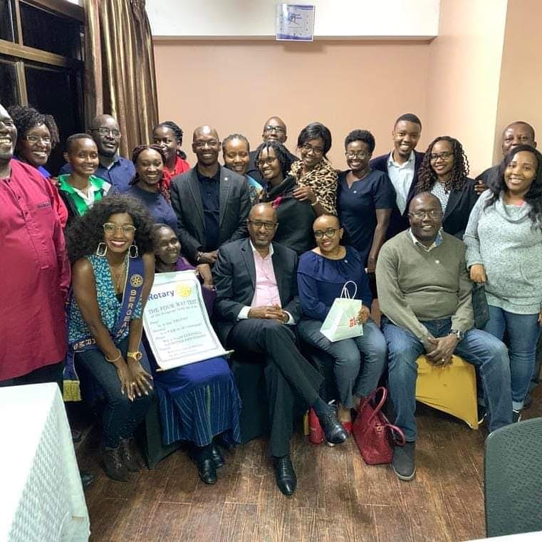 Club members gathered around a framed Four-Way Test certificate at an early club meeting.